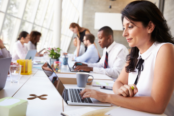 Woman working on a laptop in a busy office 